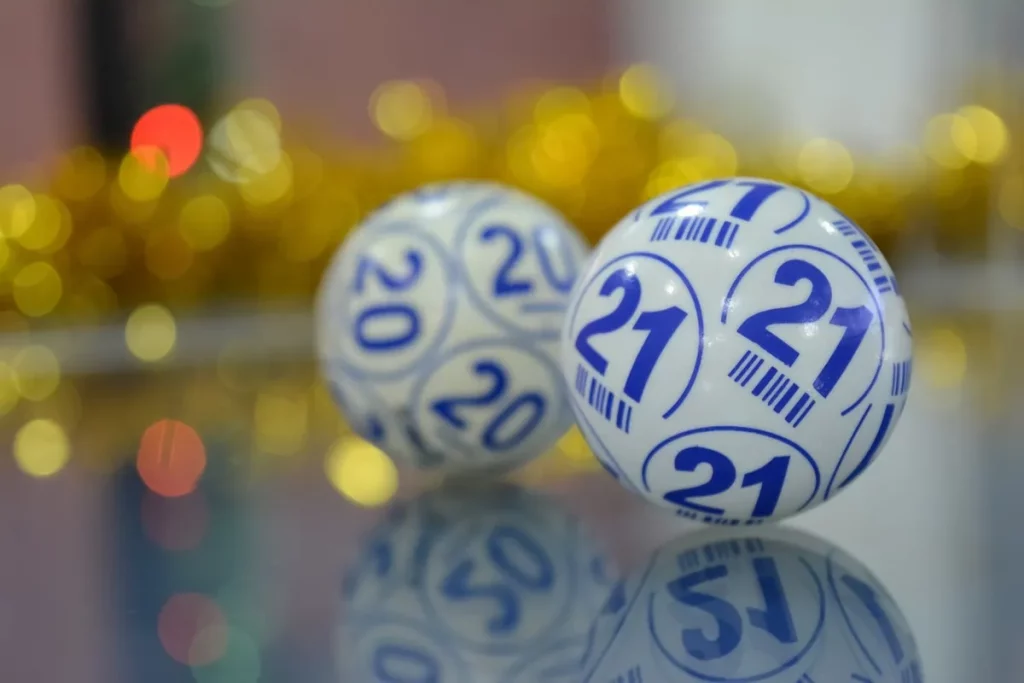 Bolas de loteria brancas com números azuis refletidas em uma superfície de vidro.