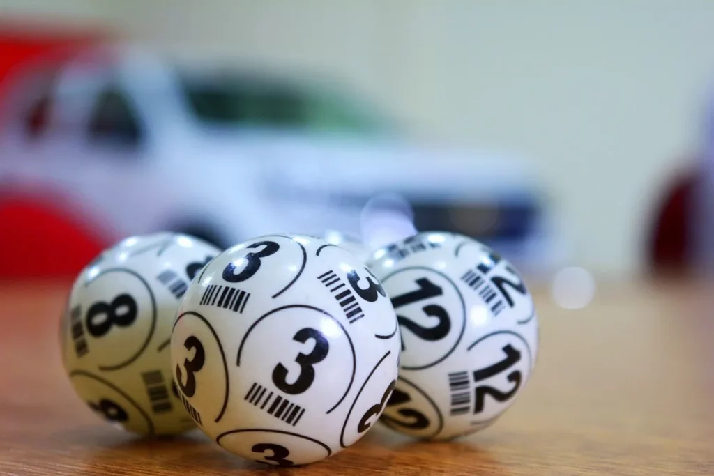 Bolas de loteria numeradas sobre uma mesa de madeira com fundo desfocado.